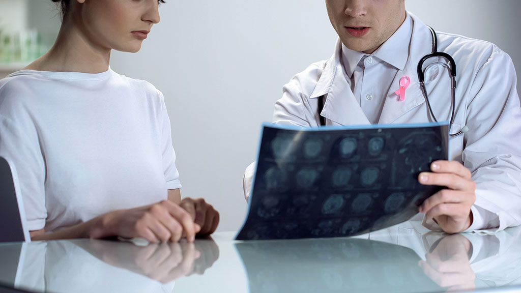 Closeup of a Gynecologist Sitting Beside a Female Patient Showing Her Abnormal Mammogram Results