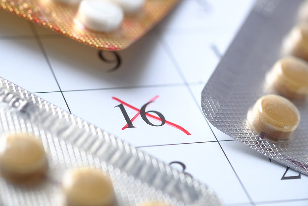 Closeup of Birth Control Pills on a Calendar With an X Marked Over a Specific Date Period Stop on Birth Control