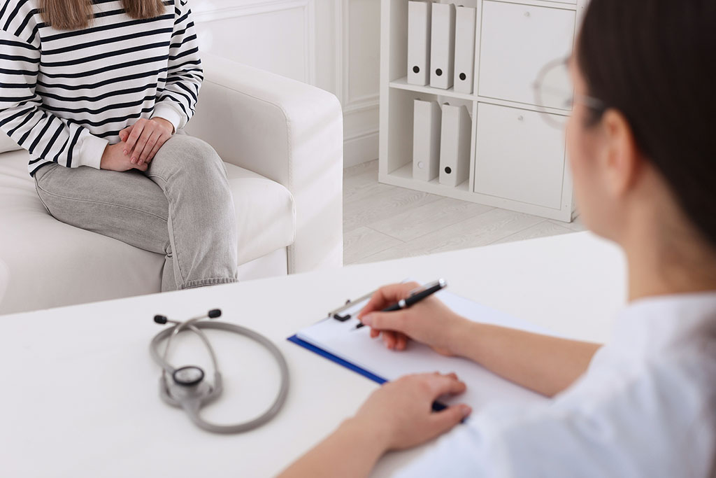 Closeup Of A Gynecology Doctor Writing On A Clipboard With A Patient Sitting On A Couch In Front Of Her HPV Vs Herpes